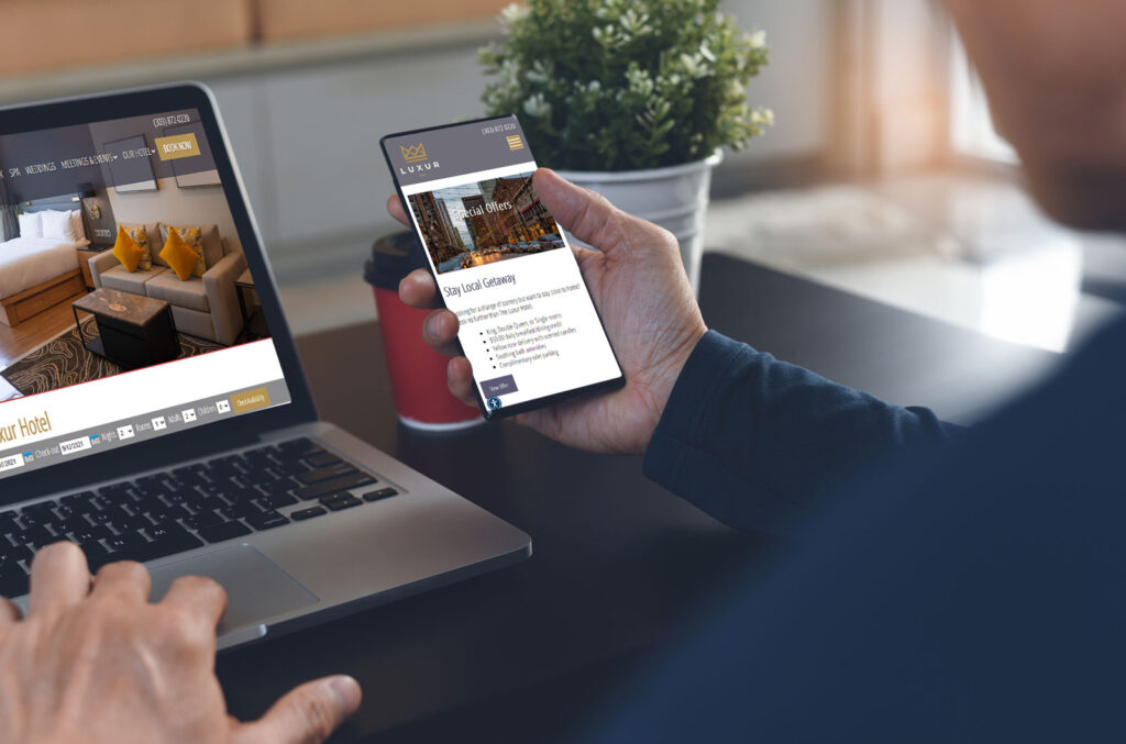 rezStream-TCMS-Website Person on phone and computer looking at a hotel website.