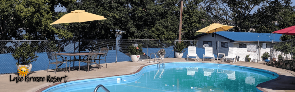Outdoor pool area at Lake Breeze Resort in Lake of the Ozarks with patio seating, umbrellas, and lakeside views